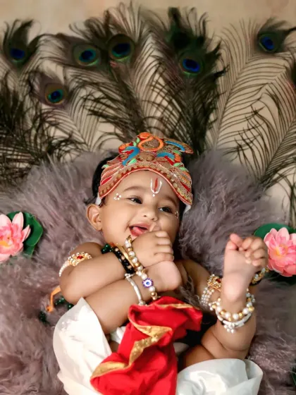 A classic and adorable baby pose, this little Krishna playfully chews on his toe while lying on a fluffy rug.