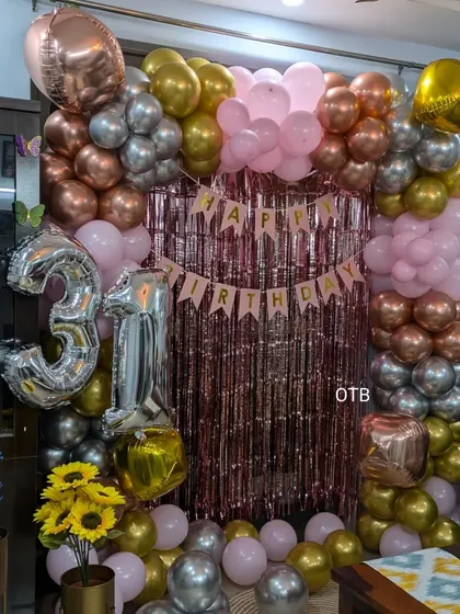The full view of the 31st birthday backdrop, featuring a rose gold shimmer curtain and a multi-toned balloon frame.