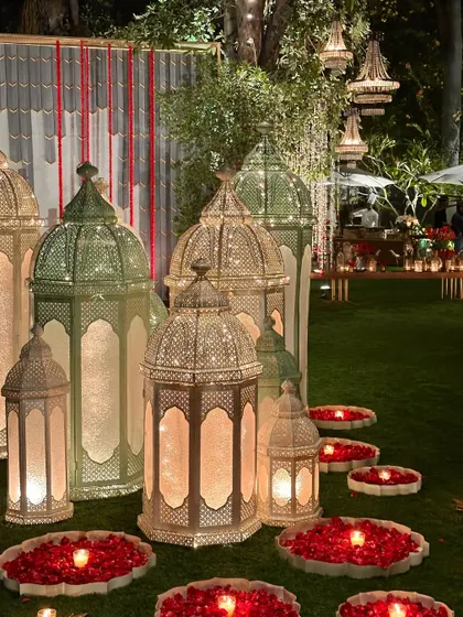 Large Moroccan lanterns on the lawn, surrounded by rose petals, creating a magical glow.