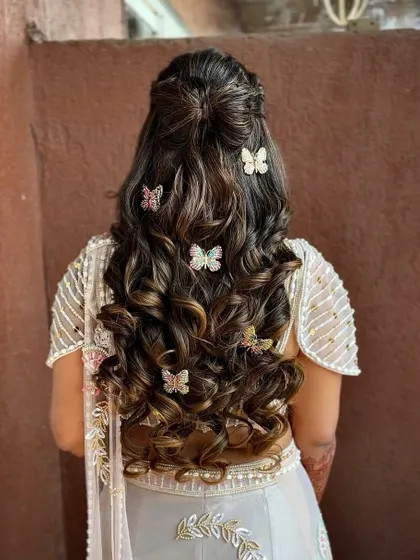 A whimsical half-updo with tight curls, decorated with beautiful butterfly clips.