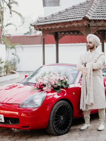 The groom stands confidently next to a red convertible, ready for his grand entrance. This shot is all about style, confidence, and making a statement on the wedding day.