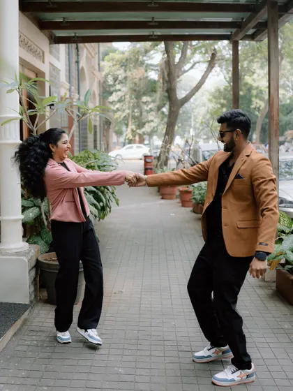 A playful moment captured as a couple holds hands and dances on a city sidewalk. Their genuine smiles and movement show the fun, relaxed vibe of my couple sessions.