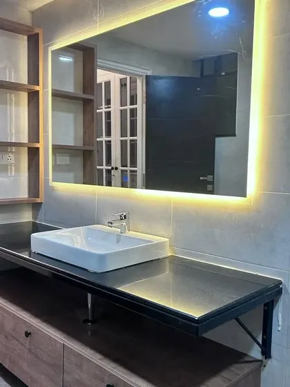 Another view of the spacious bathroom vanity, highlighting the sleek countertop and the warm glow from the backlit mirror.