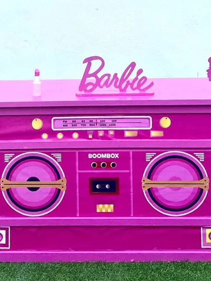 This Barbie-themed boombox table is a perfect centerpiece for a retro-inspired party. It's a functional and fun prop that serves as a cake table or DJ booth.