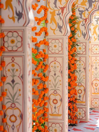 A detailed view of the hand-painted pillars at the entrance. The Mughal-inspired motifs and garlands of fresh marigolds showcase our commitment to authentic and artistic details.