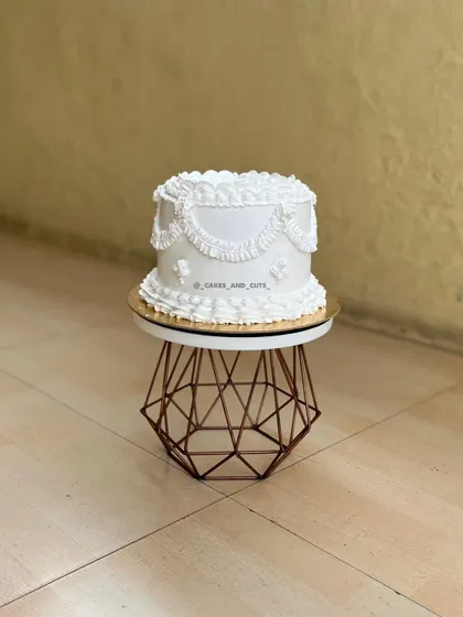 A full view of the white vintage cake with its intricate, hand-piped buttercream details.