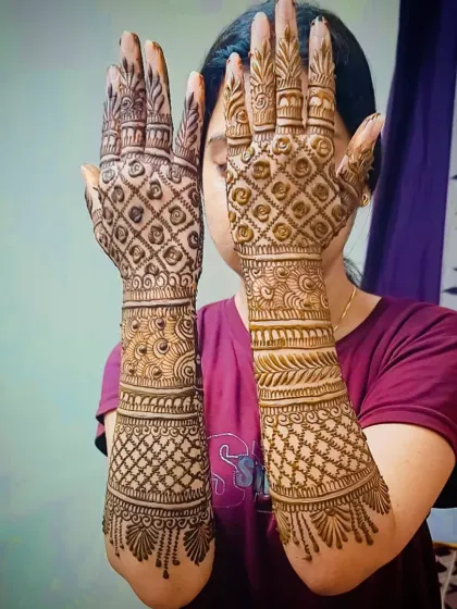 A clear, straight-on view of a full-coverage jaali design on the back of the hands, extending up the forearms.