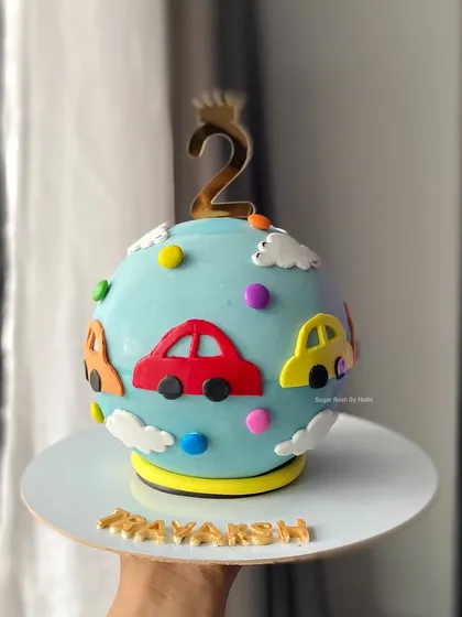 A unique car-themed sphere cake for a second birthday. This globe-shaped piñata cake is covered in cute, colorful cars and is sure to be a smash hit at the party.