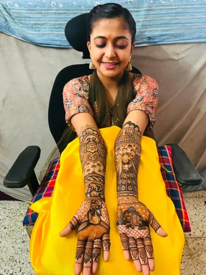 A smiling bride proudly shows her full-arm portrait mehndi, a testament to the detailed and personalized work I do.