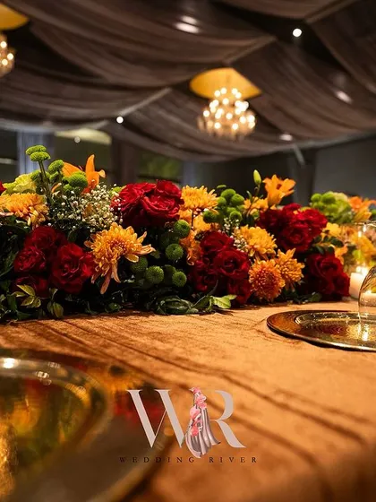 Another angle of the long floral table runner, showing how it complements the gold charger plates and the warm, velvety tablecloth.