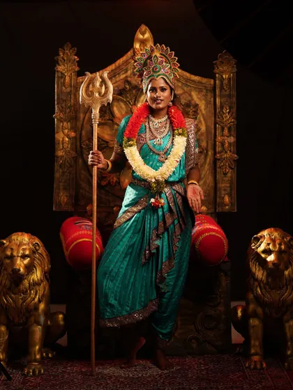 A full-length shot of the Devi costume on a throne, surrounded by lion statues, creating a majestic and powerful scene.