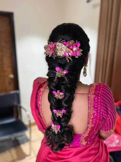 An intricate braid decorated with elaborate pink and gold floral accessories. This is a very festive and decorative style, perfect for a bride who loves bold accessories.