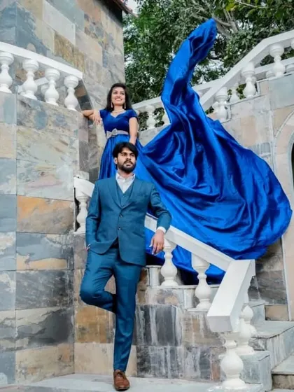 The dramatic trail of the electric blue gown creates a stunning visual as it flows down the stairs, making for a powerful and artistic couple portrait.
