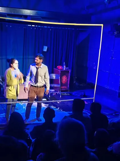 A scene from a student showcase, where actors use a simple frame to create a powerful visual metaphor on stage.
