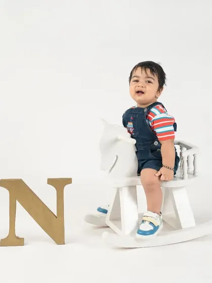 A wide shot showing the full setup for this little rider's first birthday, complete with a rocking horse and "ONE" letters.