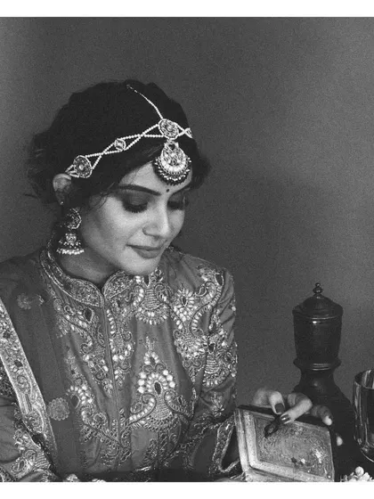 A timeless black and white portrait capturing the elegance of this vintage-inspired bridal look. The intricate embroidery on the high-neck blouse and the delicate matha patti are the stars of the show.