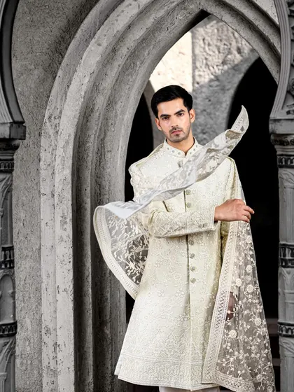 An ethereal ivory sherwani with delicate embroidery, paired with a matching embroidered dupatta. This look is perfect for a groom who wants a sophisticated and regal look for his wedding day.
