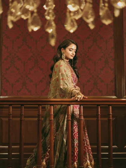 A beautiful shot of the bride on the grand staircase. The chandelier and rich decor add to the regal feel of her Sufi night look.