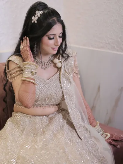 The bride admiring her henna, a classic pose that also shows off her beautiful hairstyle and the shimmer on her eyelids.