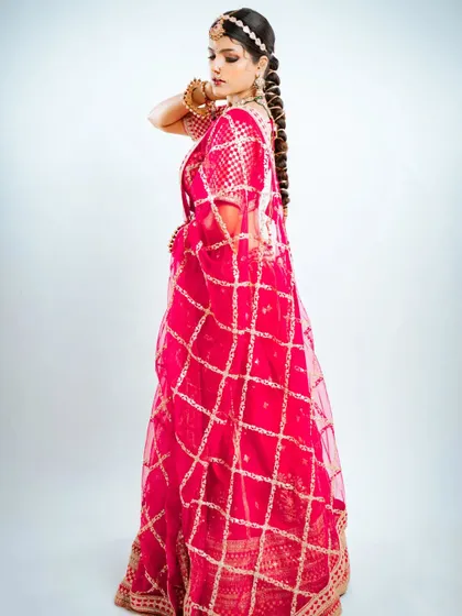 The back view of the lehenga, showcasing the detailed work on the dupatta and the traditional braided hairstyle.