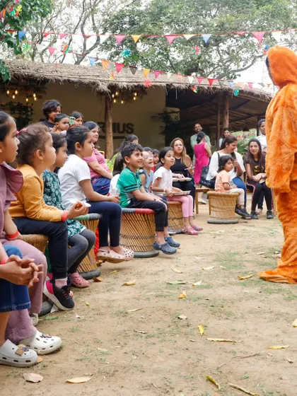 Children captivated by a storyteller in a costume during the Jungle Holi event.
