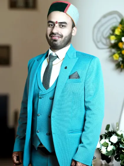 A smiling groom portrait, capturing a moment of happiness and excitement. The combination of formal wear and cultural headwear is beautifully showcased.