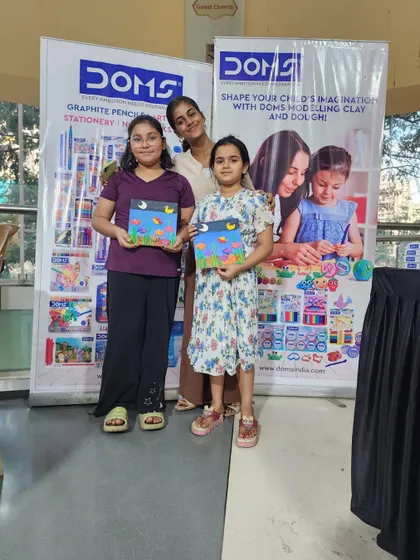 Two sisters proudly showing off the paintings they created. It is wonderful to see siblings sharing a creative hobby.