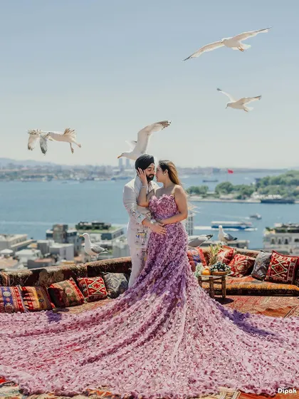 A breathtaking pre-wedding portrait in Turkey, with the bride's magnificent floral gown cascading over a rooftop overlooking the Bosphorus as seagulls fly by. This is the kind of epic, romantic photography I specialize in.
