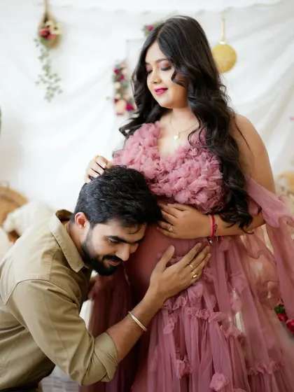 A classic and heartwarming pose. The dad-to-be kneels to listen to the baby bump, sharing a special moment with his partner.