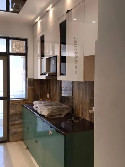 Another angle of the Kendriya Vihar kitchen, highlighting the overhead cabinets with integrated profile lighting. The black-tinted glass sections break the monotony of the white and provide a space to display crockery.