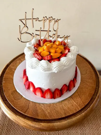 Celebrating summer with this fresh fruit cake. It's a light vanilla cake filled with layers of fresh cream and fruit, topped with mangoes and strawberries and decorated with sliced strawberries around the base.