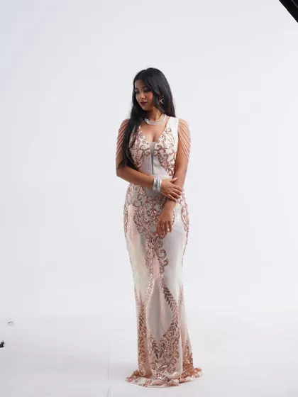 A graceful pose in the white and rose gold sequin gown, showcasing its sleek and glamorous design.