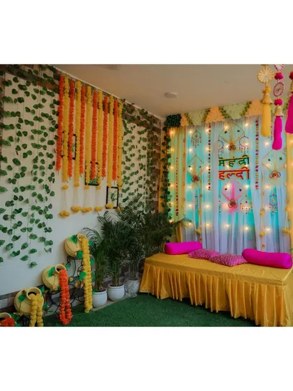 A wide shot of the vibrant and colorful decor for a home-based Mehndi and Haldi ceremony.