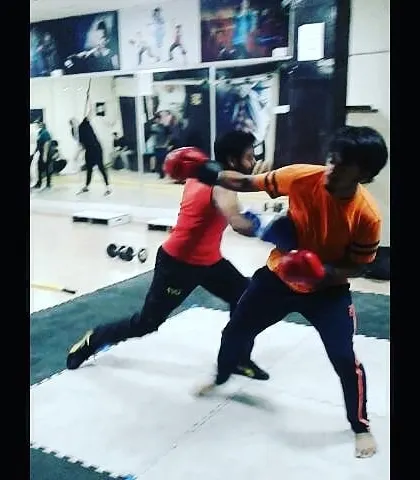 Two students engage in a controlled boxing sparring drill during an MMA class. This practice is essential for learning timing, distance management, and how to react under pressure.