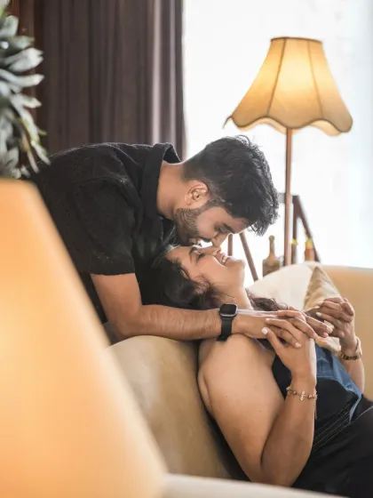 A warm and intimate moment under the soft glow of a vintage lamp. The groom's tender kiss on the bride's forehead is a perfect example of capturing quiet love.