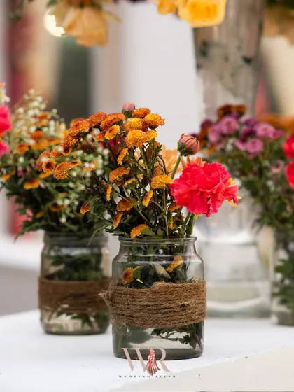 A close-up of the simple, rustic centerpieces. We used glass jars wrapped in jute twine and filled them with colorful, wildflower-style arrangements to enhance the relaxed, bohemian feel of the event.