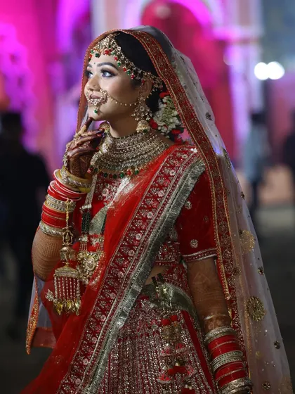 A side profile of our beautiful bride, showcasing the detailed hair and makeup. The dupatta is set perfectly to frame her face, highlighting the flawless finish of her bridal glam.