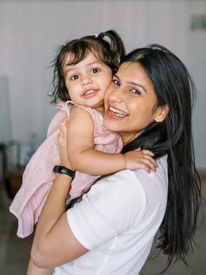 A mother holding her daughter, both looking happy and relaxed. A beautiful portrait that captures their close bond.