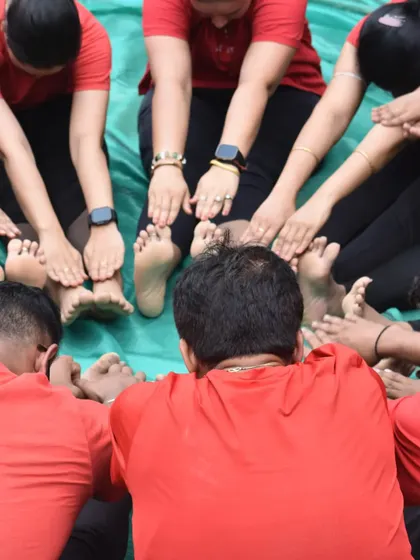 A group performing a seated forward bend in a circle. This synchronized movement promotes a feeling of connection and shared purpose.