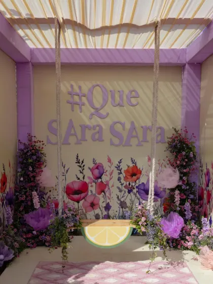 A fun photo booth with a floral swing and the couple's wedding hashtag, #QueSaraSara, set against a watercolor flower backdrop.