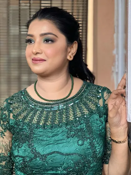 A stunning, filter-free party makeup look. This features a sophisticated green smokey eye that complements her emerald green dress, perfect for a reception or evening event.
