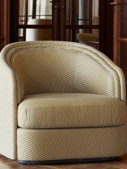A detailed shot of the "Boromeo" armchair, emphasizing the texture of the fabric and the graceful lines of its cradling backrest. This view highlights the meticulous craftsmanship and design that goes into each of our upholstered pieces.