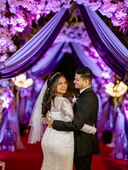 A beautiful portrait under the floral archway. The bride looks back with a smile, her elegant hair and makeup looking flawless.