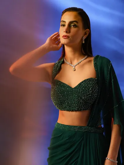 A model wearing a stunning emerald green beaded bustier and draped skirt. The diamond necklace adds a touch of luxury, making this a perfect look for a high-end jewelry collaboration.