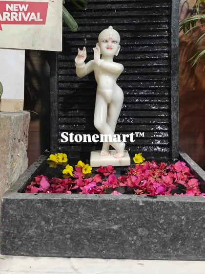 The Kanha Ji fountain decorated with floating flower petals. The contrast between the white marble, dark granite, and colorful flowers is stunning.