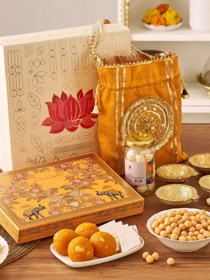 This corporate festive gift includes a box of sweets, a jar of nuts, decorative diyas, and a beautiful yellow potli bag, making it a perfect token of appreciation during the Diwali season.