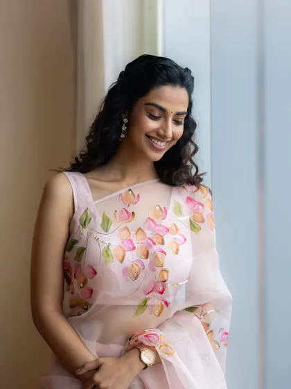 A candid and happy shot from the pink floral saree series. The natural light and relaxed pose create a feeling of effortless beauty and charm.