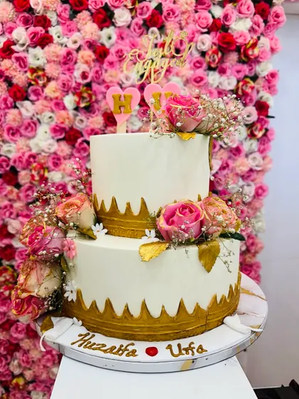 A grand 5 kg Dutch Truffle engagement cake. This two-tiered design features beautiful pink roses, baby's breath, and delicate gold lacework.