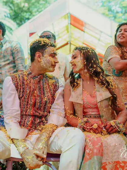 The couple sharing a look of love while covered in turmeric paste and flower petals.