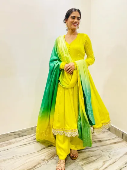 This lemonade yellow Anarkali set is perfect for a Haldi or Mehndi ceremony. The flowing silhouette and contrasting green dupatta create a look that is both joyful and effortlessly elegant.